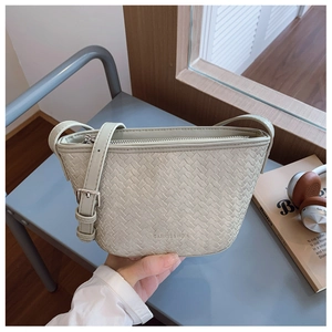 Detail of light green woven bucket bag with metal zipper and adjustable leather strap