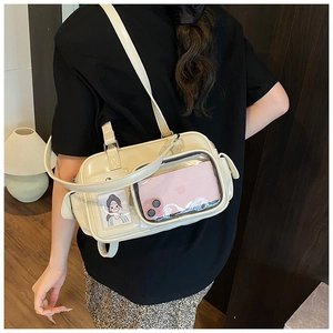 Detail of cream white bowling bag showing transparent PVC window for doll display and phone