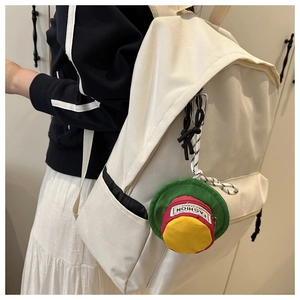 Detail of white canvas backpack featuring a colorful mini hat charm and side pockets