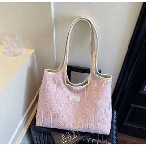 Detailed close-up of pink quilted tote bag with colorful zigzag embroidery and leather label