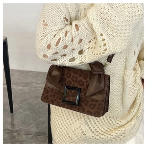 Detail of leopard print crossbody bag with large black buckle and slim leather strap