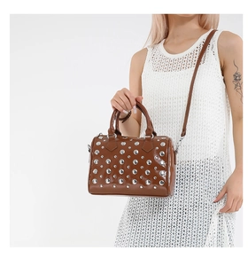 Detail of silver rivets on a brown leather Boston bag with double handles and strap