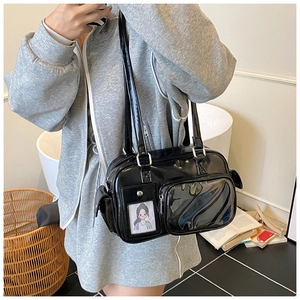 Detail of black glossy shoulder bag featuring functional pockets and transparent PVC slot