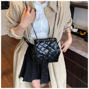 Detailed view of black quilted leather backpack with gold chain strap worn by a model
