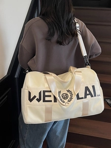 Large cream gym bag with black logo shown in a lifestyle indoor staircase setting