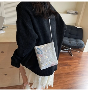 Detail of embroidered butterfly phone bag on a model in a cozy office setting