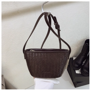 Close-up of brown woven leather bucket bag with adjustable strap and textured pattern