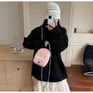 Detail of pink quilted mini backpack with metallic chain strap and twist lock