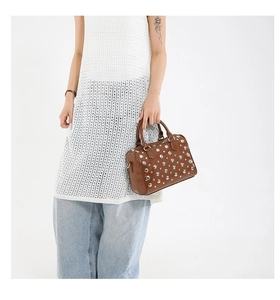 Close-up of brown Boston bag featuring silver studs and cylinder double handles