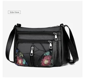 Side view of black soft leather crossbody bag with colorful floral embroidery details