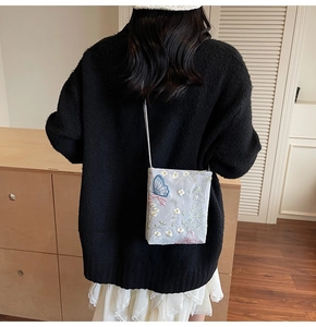 Detailed embroidery of blue and pink butterflies on a beige minimalist bucket bag