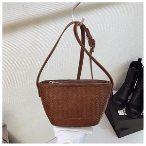 Detail of dark brown woven texture handbag with brand logo and adjustable shoulder strap
