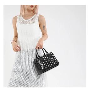 Detail of black bowling handbag with silver studs and polished patent leather finish