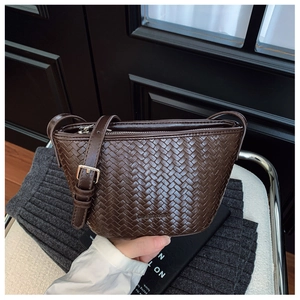Close-up of dark brown woven texture on a bucket bag with silver metal strap buckle