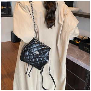 Detail of black quilted leather backpack with silver chain straps worn by a model