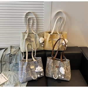 Group display of colorful striped canvas tote bags with pearl straps and plush charms