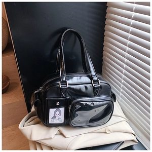 Detail of black glossy handbag featuring transparent window pockets and dual handles