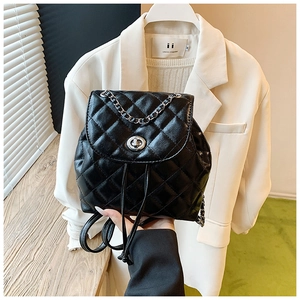 Detail of black quilted leather backpack with metal chain strap and twist-lock closure