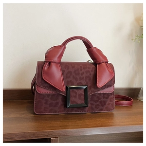 Detail of burgundy leopard print suede handbag with large black buckle and knot handle