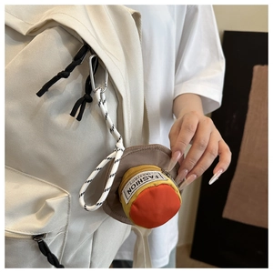 Mini hat-shaped pouch with Fashion Instinct text hanging on a white backpack