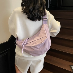 Minimalist lavender nylon dumpling bag with adjustable strap worn as a crossbody bag