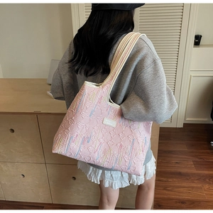 Detail of pink quilted tote bag with wavy embroidery and branding shown on model