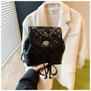 Close-up of black quilted backpack with silver twist lock and chain strap detail