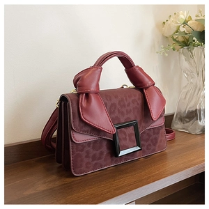 Detail of burgundy leopard print handbag with unique knotted handle and square buckle