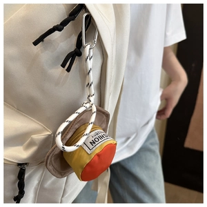 Detailed view of the yellow hat-shaped mini earphone pouch hanging on a backpack