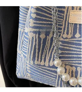 Detail of geometric weave canvas bag with metal chain and pearl shoulder strap accent