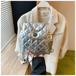 Detail of silver quilted backpack featuring a metallic finish and elegant chain straps