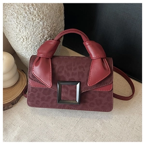 Detail of dark red leopard print crossbody bag with knotted handle and black buckle