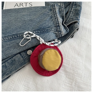 Detail of a round mini earphone case with a metal carabiner and tricolor nylon design