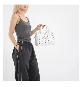 Detail of white Boston bag featuring silver metal rivets and smooth leather texture
