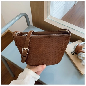 Close-up of brown woven bucket bag featuring adjustable strap and silver metal buckle