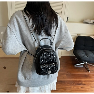 Detail of quilted leather mini backpack with sparkling crystal studs and chain strap