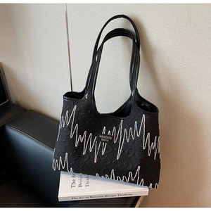 Detail showing wavy line pattern and WEGOCO BAGS label on a black textured tote bag