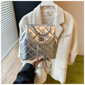 Close-up of silver quilted mini backpack with metallic chain and twist-lock closure
