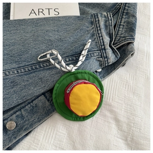 Detail of colorful round mini pouch with zipper and carabiner on denim jacket
