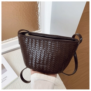 Detail view of dark brown woven leather bucket bag with silver zipper and slim shoulder strap