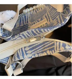 Detailed shot of a smooth silver zipper and pearl handle on a geometric tote bag