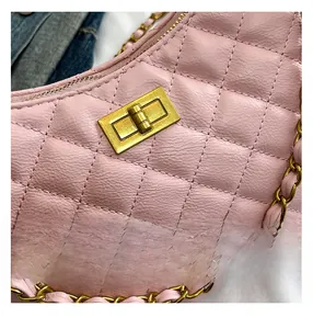 Close-up of pink quilted faux leather bag featuring a vintage gold square lock and chain strap