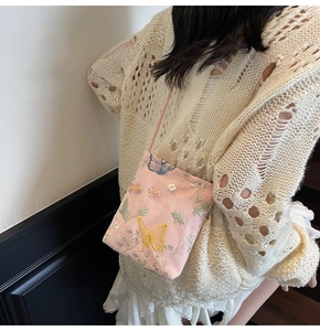 Detail of pink embroidered crossbody bag with butterfly patterns and flower stitchings