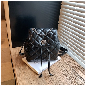 Detail of black quilted leather backpack with silver chain and metal turn-lock closure