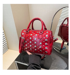 Detail of red glossy boston bag with silver metal rivets and sturdy dual handles