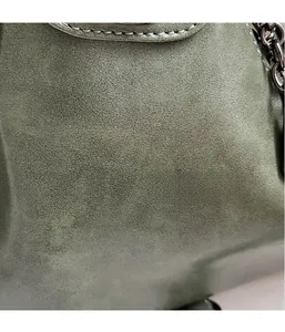Dettaglio in pelle testurizzata verde oliva con cuciture bianche e catena in metallo scuro