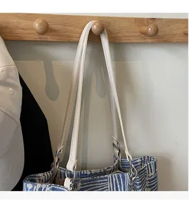 Detail of blue and white striped woven tote bag with cream leather shoulder strap