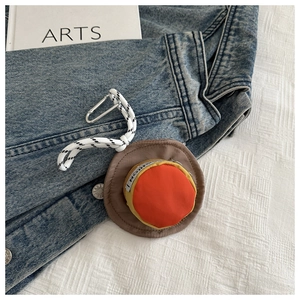 Mini hat-shaped earphone case with silver carabiner shown on denim background