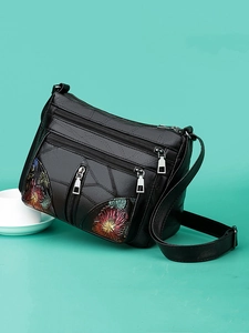 Elegant black faux leather crossbody bag with multiple zippers and floral pattern