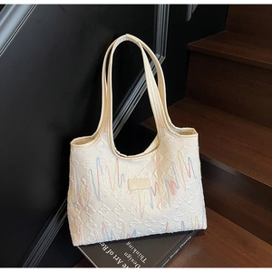 Detail of white quilted tote bag with colorful wavy embroidery and shoulder straps